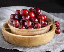 red ripe fresh cherry in a wooden bowl on a gray textile napkin