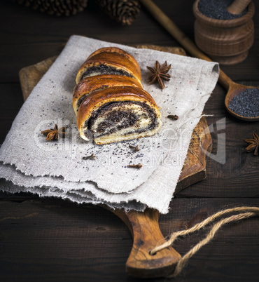 baked roll with poppy seeds on a brown wooden board