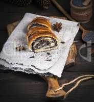 baked roll with poppy seeds on a brown wooden board