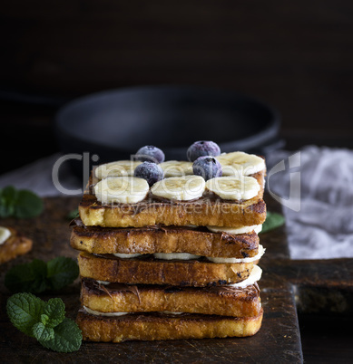 pile of square fried bread slices with chocolate and banana slic