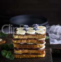 pile of square fried bread slices with chocolate and banana slic