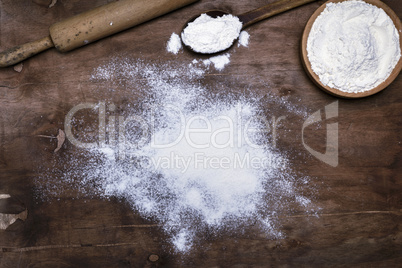 scattered white wheat flour on a brown wooden surface