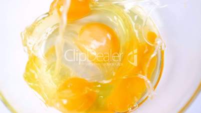 Fresh organic egg falling into glass bowl slow motion