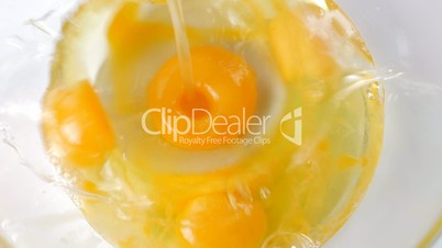 Fresh organic egg falling into glass bowl