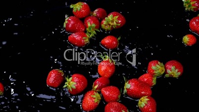 Strawberries falling on water on black background