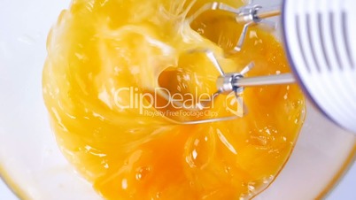 Beating eggs with electric mixer in glass bowl