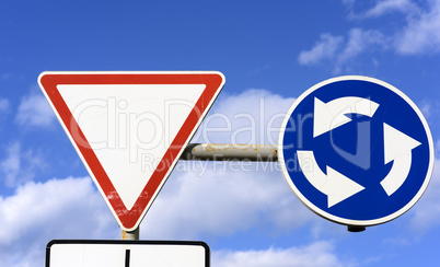 two road signs against a blue sky with white clouds