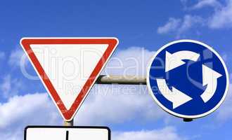 two road signs against a blue sky with white clouds