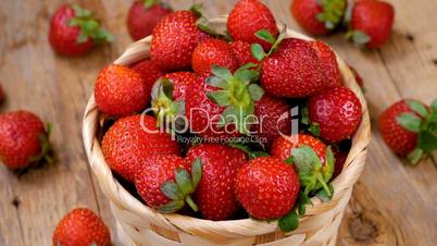 Fresh strawberries in basket spinning on wooden table