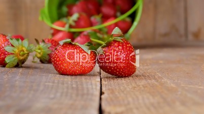 Fresh strawberries falling from bucket on wood