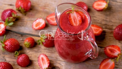 Fresh strawberry smoothie spinning on wooden table