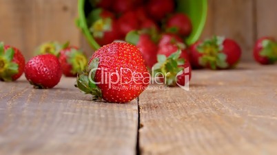 Strawberries falling from bucket on wood