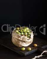 ripe green gooseberry in brown paper bag on a wooden board