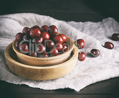 ripe red cherries in a brown wooden bowl on a brown table