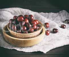 ripe red cherries in a brown wooden bowl on a brown table