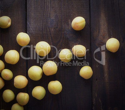 scattered ripe yellow apricots on a brown wooden table