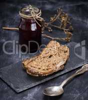 a piece of rye bread and a jar of raspberry jam