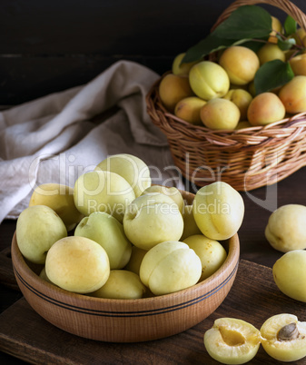 ripe apricots in a wooden bowl on a brown table