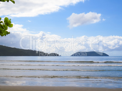 Beach and sea with waves, and island in the background.