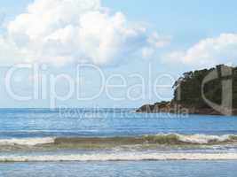 Waves on the beach with island in the background.