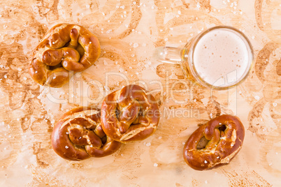 Several salty cooked pretzel and lager beer seen from above