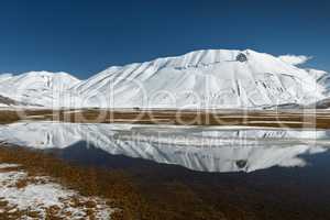 Sibillini mountains reflected in the water with snow