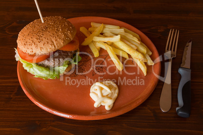 Hamburger fried potatoes and mayonnaise on an earthenware plate