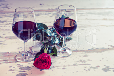 Two glasses of red wine and a rose