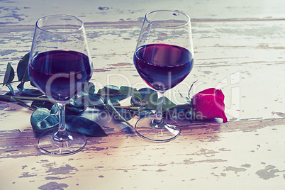 Two glasses of wine and a red rose