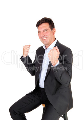 Man sitting on chair with hands in fist, victory