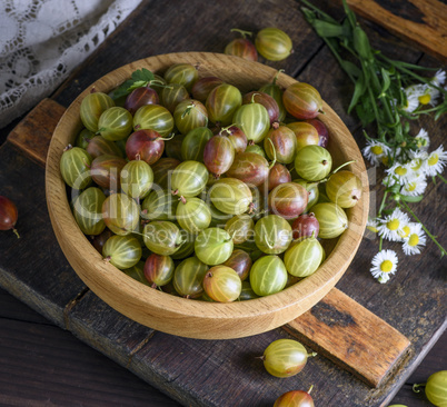 round wooden bowl with green gooseberries