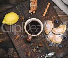 brown ceramic cup with black tea and croissants on a wooden boar