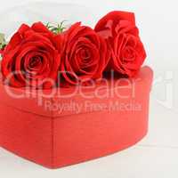 Gift box in the form of heart and scarlet roses on white wooden