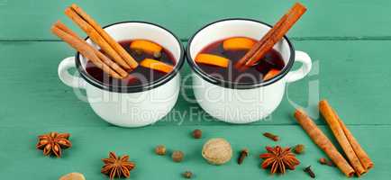 Hot red mulled wine on wooden background with christmas spices,