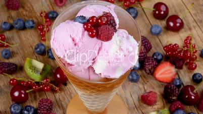 Forest fruits ice cream in cup rotating on wooden table