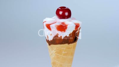 Vanilla ice cream in cone rotating on blue background