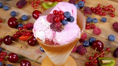 Fruit ice cream in cup rotating on table full of forest fruits