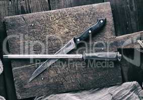 old knife and a sharpener on a brown wooden cutting board