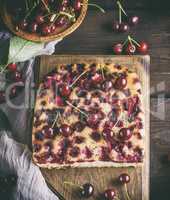 baked cake with cherries on a brown wooden board