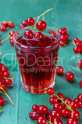 Red currant juice in glass with fruits on wood table