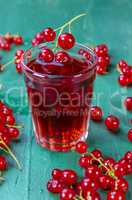 Red currant juice in glass with fruits on wood table