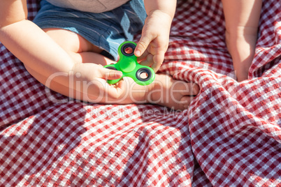 Baby Boy Sitting on Picnic Blanket Playing With Fidget Spinner