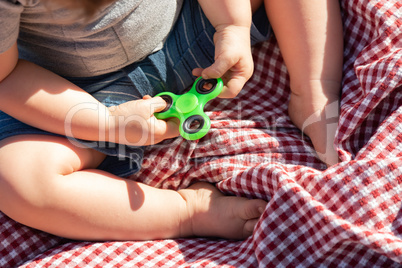 Baby Boy Sitting on Picnic Blanket Playing With Fidget Spinner