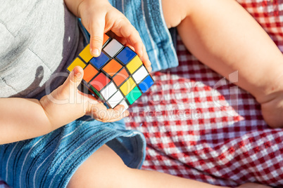 Baby Boy Sitting on Picnic Blanket Playing With Cube Puzzle