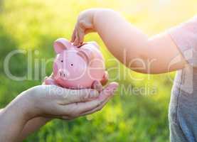 Woman Holds Piggy Bank While Baby Boy Puts Coins Inside