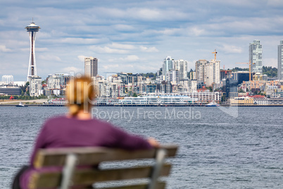 Woman Sitting on Bench Looking At The Seattle, Washington Skylin