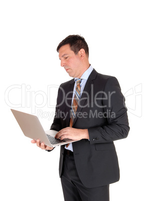 Business man reading on his laptop and standing