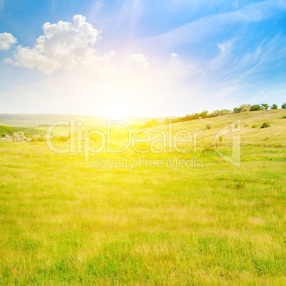 Hilly green fields and sunrise on a blue sky.