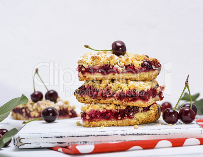 a stack of baked slices of a pie with cherry berries on a white