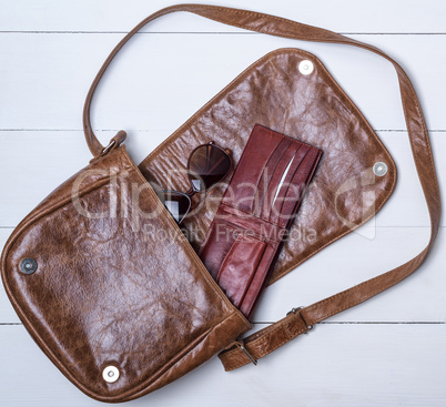 open brown leather bag with purse and glasses